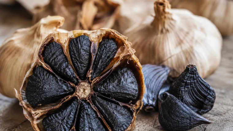 Imagen ilustrativa de una cabeza de ajo negro abierta.