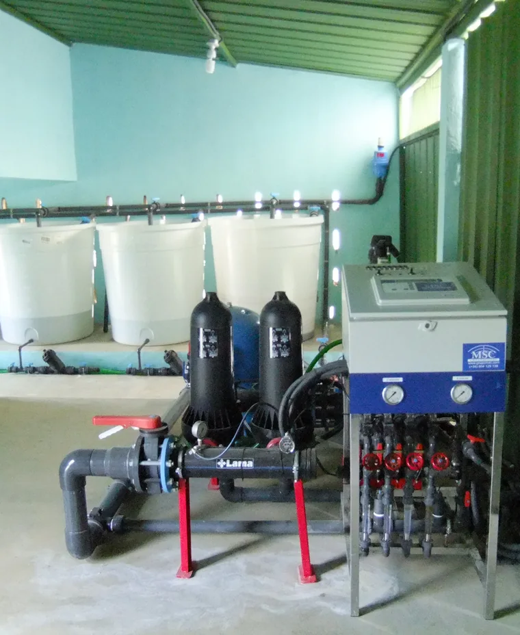 Sala del sistema de riego con tanques, filtros, tuberías y panel de control.