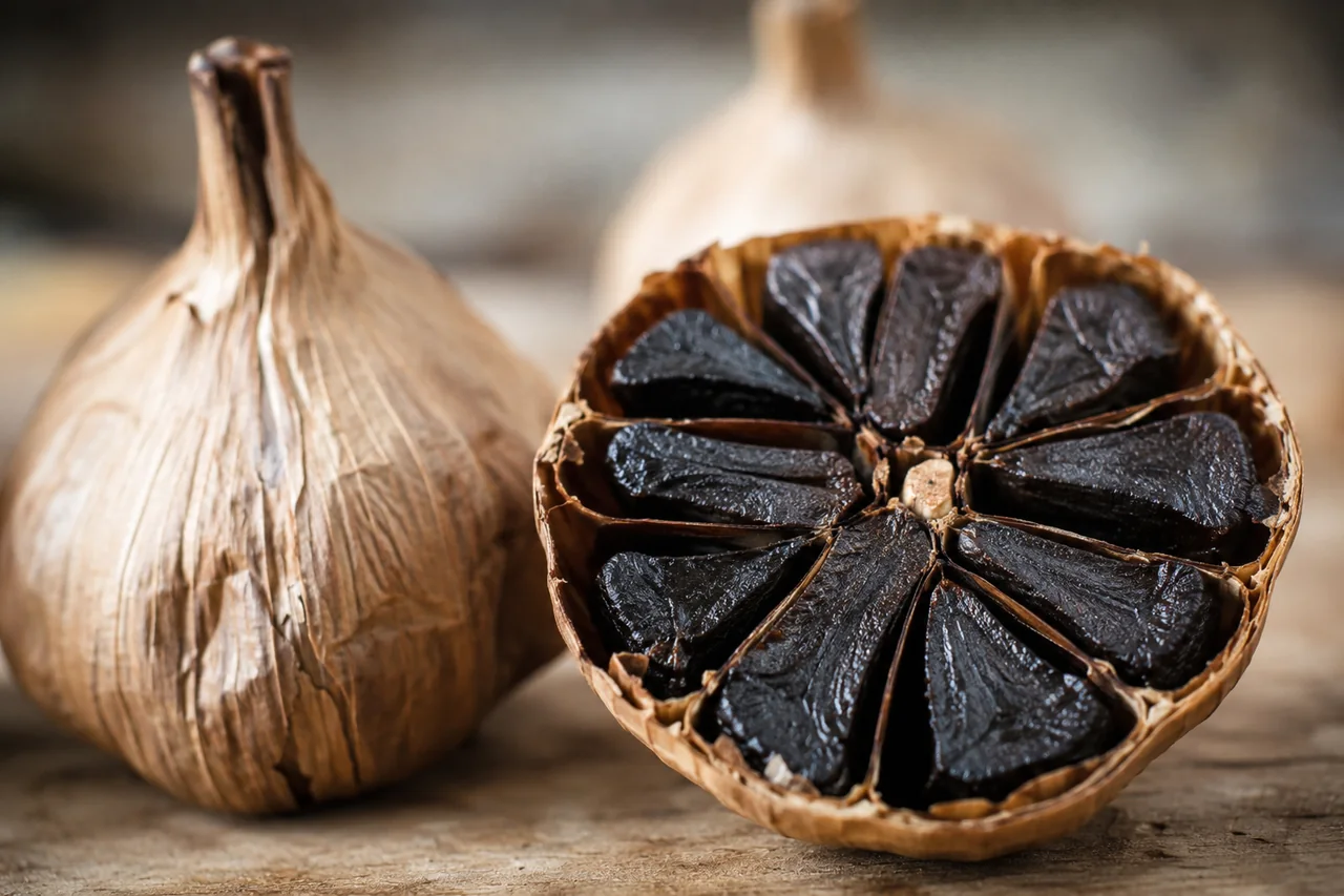 Imagen ilustrativa de una cabeza de ajo negro abierta.
